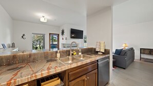 A modern kitchen with a marble countertop, double sink, and wooden cabinets. - Fabulous 1-bedroom condo overlooking Gulf course with AC in sunny San Diego (San Diego)