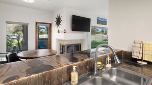 A modern kitchen with a marble countertop, a built-in sink, and a flat-screen TV mounted above the fireplace. - Fabulous 1-bedroom condo overlooking Gulf course with AC in sunny San Diego (San Diego)