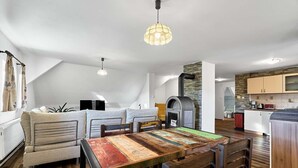 Avoin, loft-tyylinen olohuone, jossa on ruokailutila, keittiö ja oleskelualue.