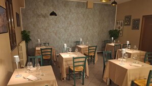 Ein Restaurant mit mehreren Tischen, Stühlen und hängenden Pendelleuchten.
