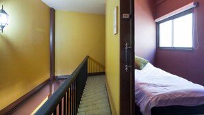 A room with a bed, a window, and a staircase. - Raw Hostel (Chiang Mai)