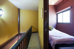 A room with a bed, a window, and a staircase. - Raw Hostel (Chiang Mai)