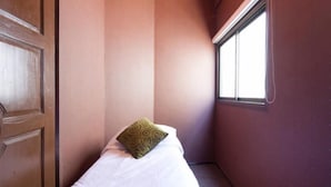 A narrow room with a single bed, a window, and a door. - Raw Hostel (Chiang Mai)