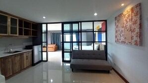 A modern interior with a kitchen, a sofa, and a large window. - Raw Hostel (Chiang Mai)