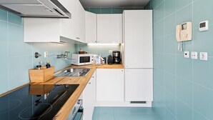A modern kitchen with white cabinets, a microwave, a coffee maker, and a wooden countertop.