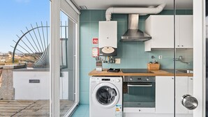 A compact kitchen with a washing machine, a stove, and a sink.