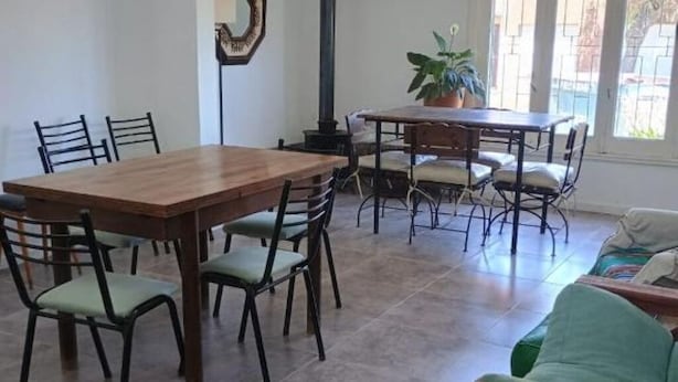 A dining area with a wooden table and chairs, a potted plant, and a sofa.