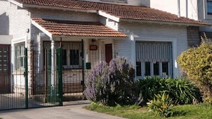 A two-story building with a tiled roof, a gated entrance, and a small garden with lavender plants.