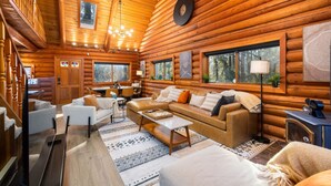 A log cabin interior with a living area, dining space, and a staircase. - Riverfront retreat with sauna & hot tub 3B2Ba (Granite Falls)