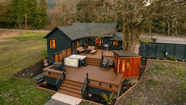 Una cabaña con terraza, mobiliario exterior y un jacuzzi.