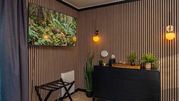 Ein modernes Zimmer mit einer schwarzen Couch, einer Wand aus Holzlamellen, einem großen gerahmten Bild und zwei Wandleuchten.