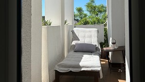 A small, enclosed balcony with a bed, a table, and a chair. - Duplex 'Sotogrande' with Shared Pool, Terrace and Wi-Fi (Sotogrande)