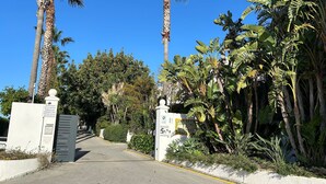 A gated entrance with palm trees and a clear sky. - Duplex 'Sotogrande' with Shared Pool, Terrace and Wi-Fi (Sotogrande)