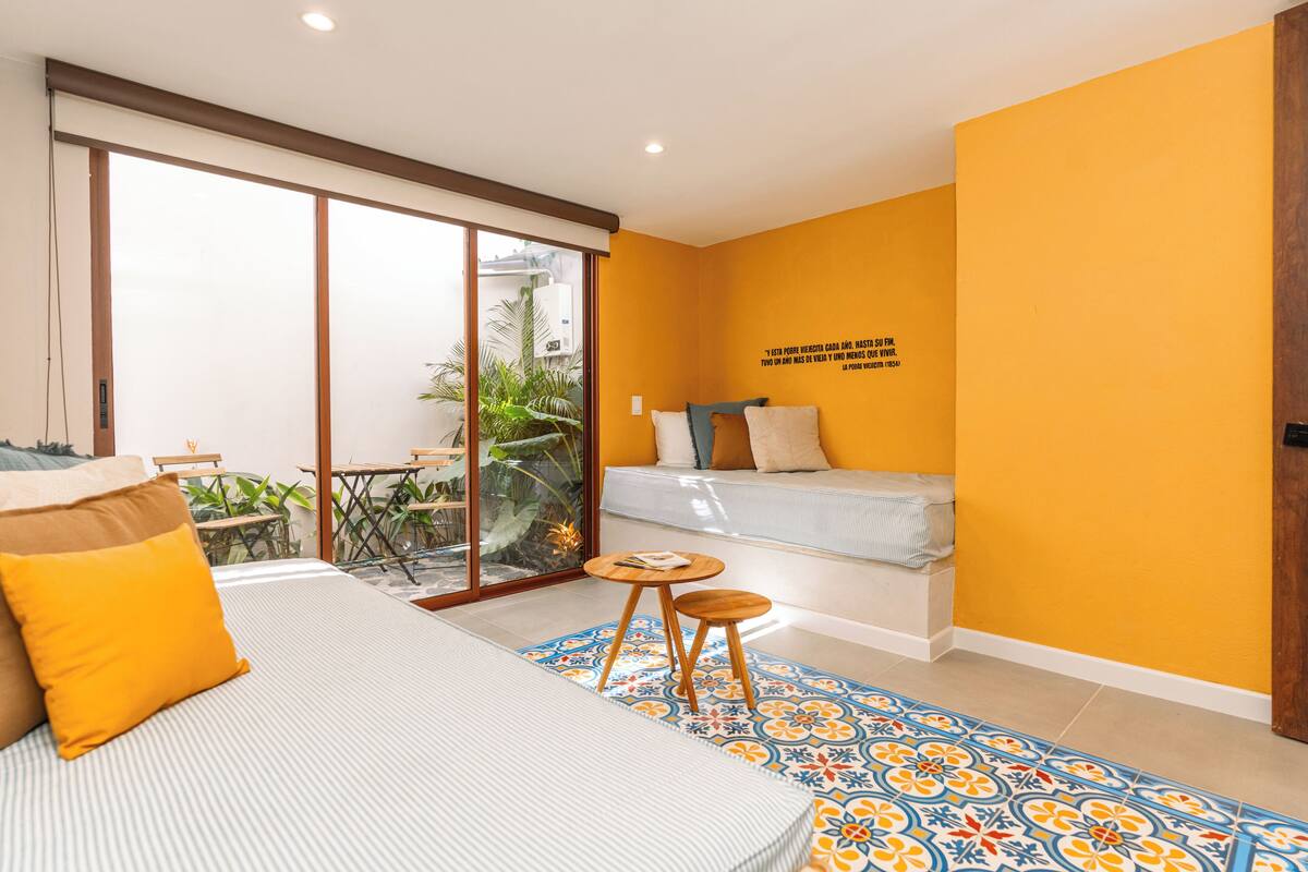 A compact hotel room with a bed, a small table, and a sofa.