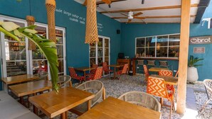 Ein Restaurant mit Holztischen und -stühlen, einem Deckenventilator und einer blauen Wand mit Schrift.