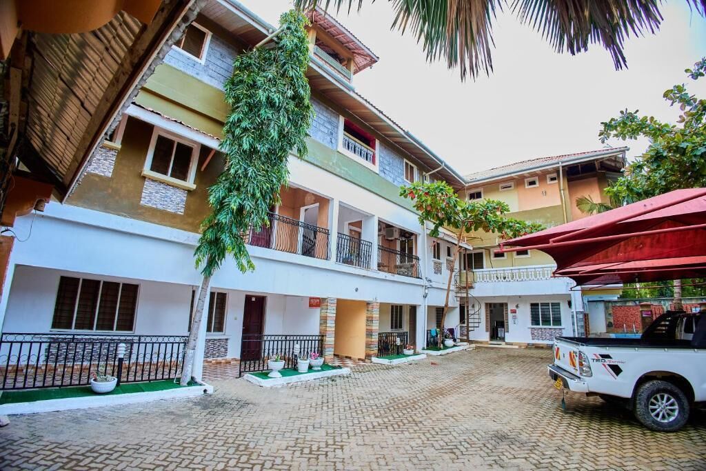 A courtyard with a white pickup truck parked, surrounded by multi-story buildings with balconies and potted plants.