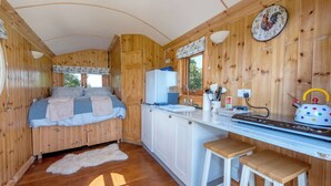 Ein Ferienhausinnenraum mit Bett, Küchenzeile, Holzwänden und einem Fenster.