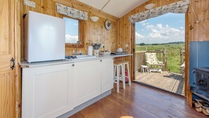 Ein Holzhütten-Interieur mit Küche, Essbereich und einer Terrasse mit Blick auf die Landschaft.