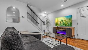 Una sala de estar moderna con una escalera, un televisor de pantalla plana y un cuadro grande.