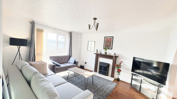 Ein Wohnzimmer mit grauem Sofa, Couchtisch, Kamin, Fernseher und Stehlampe.