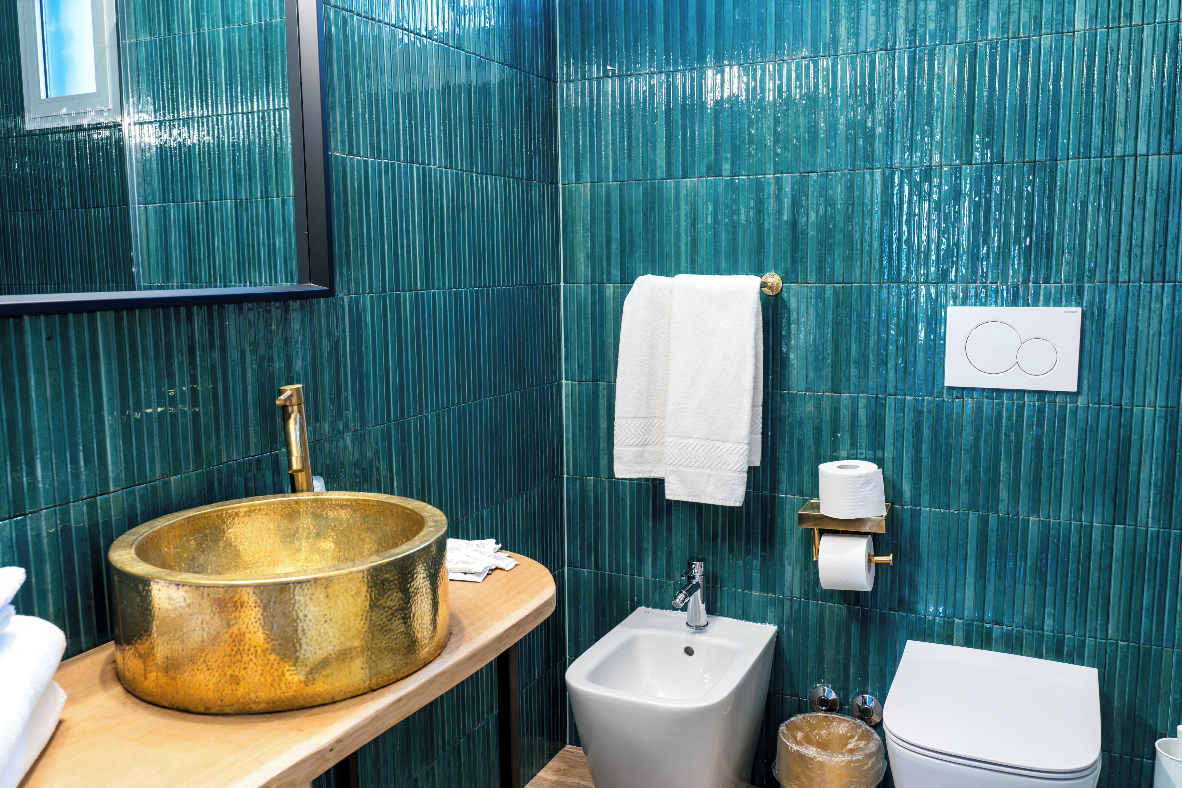 A bathroom with a gold sink, white pedestal sink, and toilet.