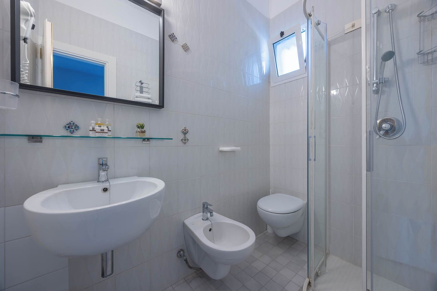 A bathroom with a large sink, a bidet, a toilet, and a glass-enclosed shower area.