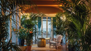 A sunlit indoor space with a seating area, large potted plants, and a view through a glass door. - Hotel Portofino Jesolo (Lido di Jesolo)