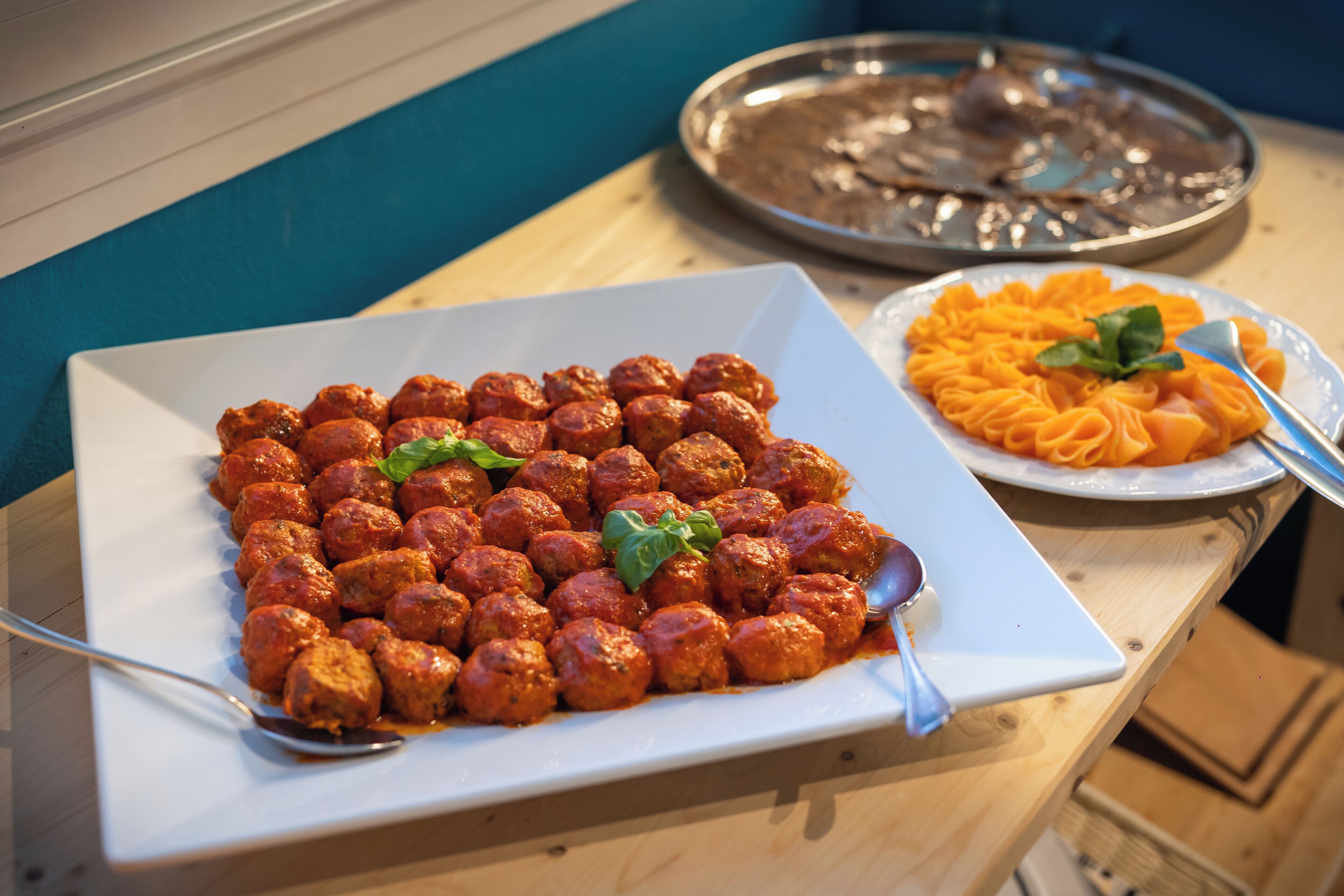 A buffet table with a plate of meatballs and a plate of pasta.
