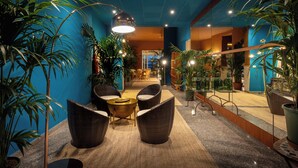 A lobby with wicker furniture, potted plants, and a bright ceiling light. - Hotel Portofino Jesolo (Lido di Jesolo)