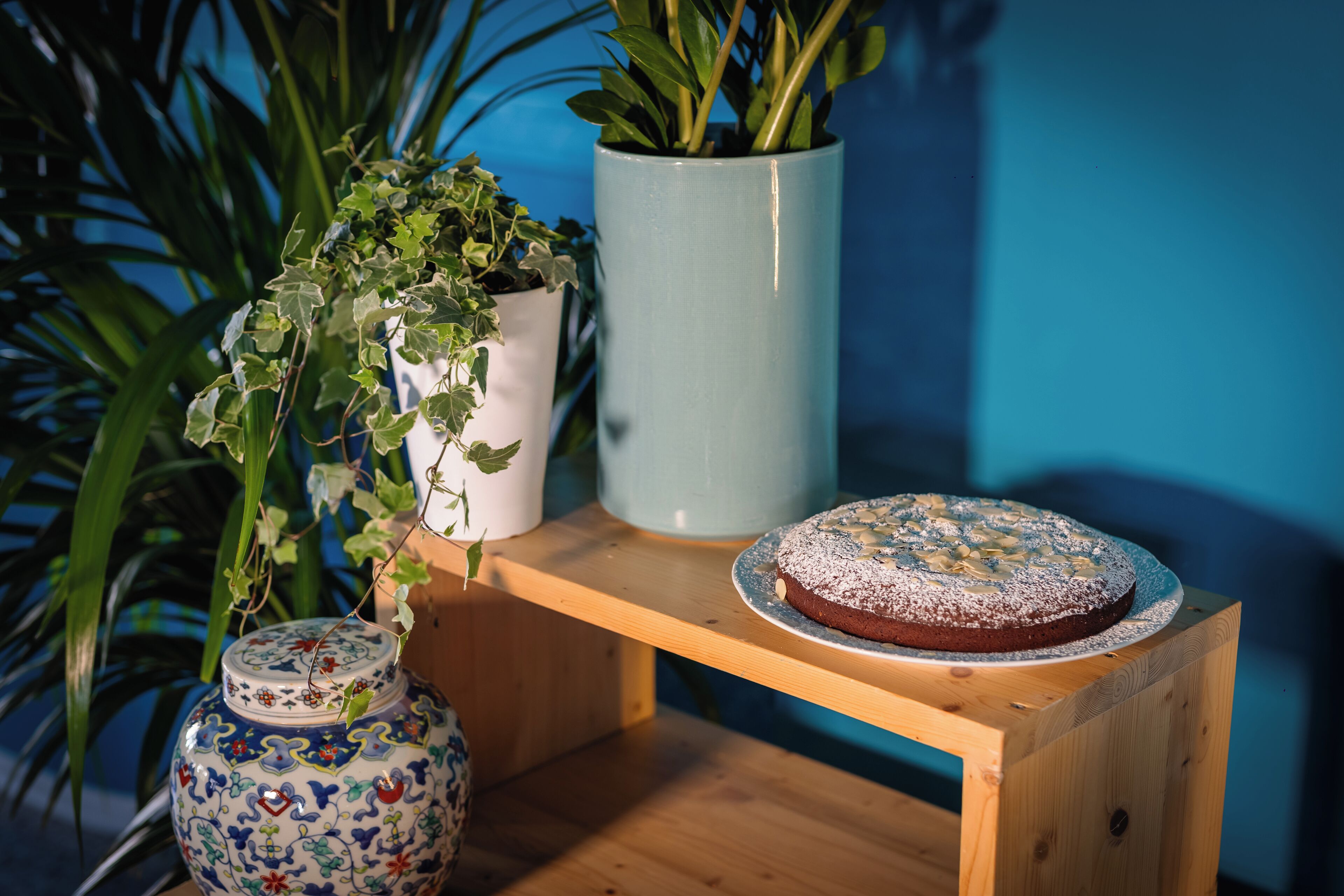 Una mesa de madera con un pastel y dos jarrones con plantas.