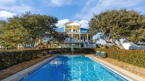 A rectangular swimming pool with a clear blue water surface, surrounded by a low hedge and two lounge chairs. - Waterfront Home w/ Pool, Private Dock & Fireplace in Newport NC (Newport)