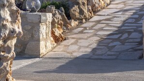 A stone pathway leading to a building with a modern design, outdoor seating, and a clear sky. - Your Private Paradise with 2 Pools & Sea Views (Rethymno)