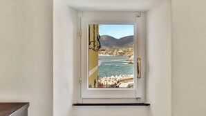 Pequena janela com vista para uma área costeira, incluindo um corpo de água e terreno rochoso.
