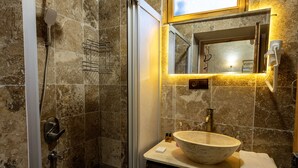 A bathroom with a shower, a sink with a large bowl, a mirror, and a towel rack. - cappadocia keyfiala hotel (Urgup)