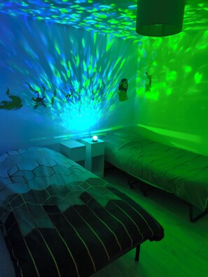A room with two beds, a nightstand, and a wall with a green light projection. - House with courtyard, 3-minute walk from the beach 🏖️ - the sea breeze 🌊 (Gravelines)