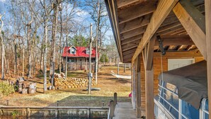A wooden deck leading to a pool area with a view of a red-roofed house in the background. - Lakefront Escape w/Private Water Access, Dock, Kayaks, & Fire Pit. Pet Friendly! (Sparta)