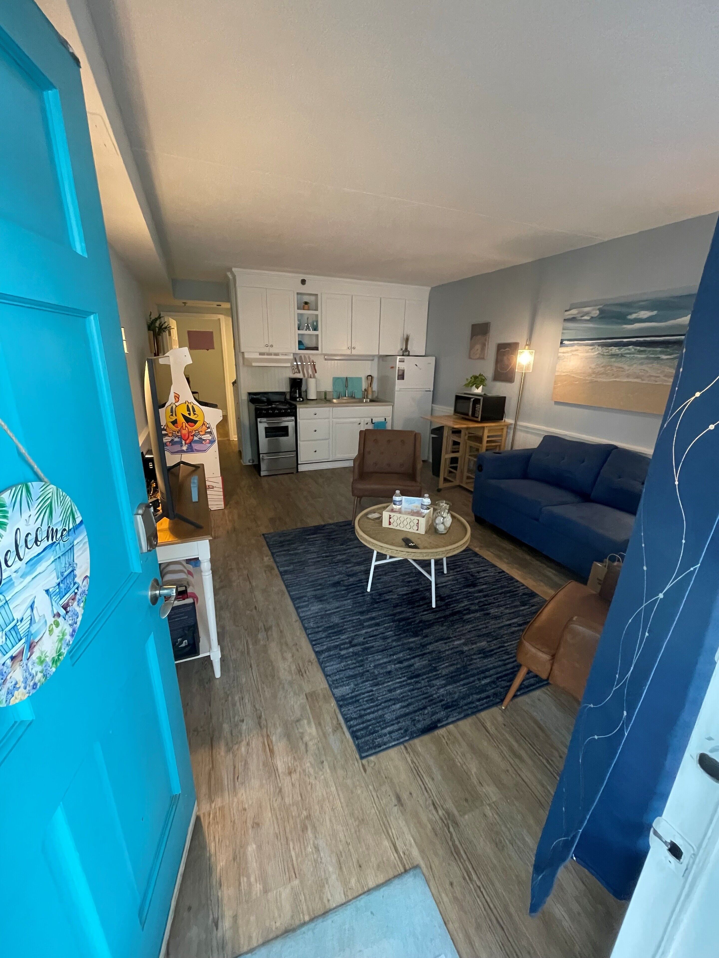 A compact living space with a kitchenette, a blue sofa, a coffee table, and a dining area.