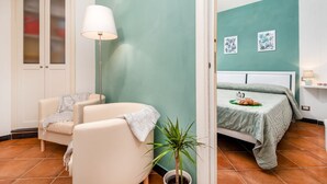 Ein Schlafzimmer mit Bett, Stuhl, Lampe, Pflanze und einer Tür.