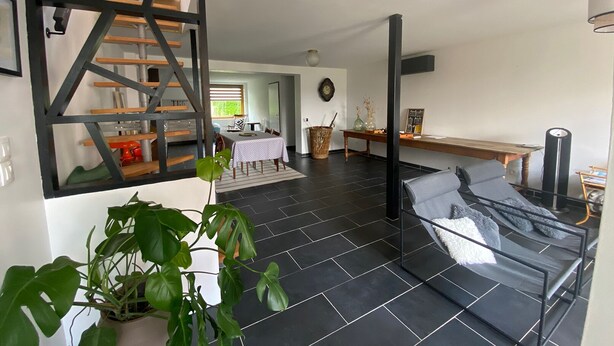 Un espacio habitable moderno con una escalera, un comedor y una cocina visible a través de una puerta abierta.