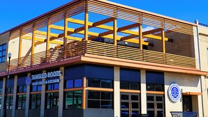 Un bâtiment à ossature en bois, sur lequel on peut lire l’inscription suivante : « Tangled Roots, bières artisanales et cuisine ».