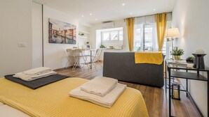 A modern hotel room with a bed, a sofa, a dining area, and a view of the cityscape. - LINDA'S HOUSE
Delightful apartment with AC in charming Venice Mainland (Venezia)