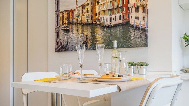 A dining area with a table set for two, featuring a white tablecloth, clear glasses, a bottle, and a plate with food. - LINDA'S HOUSE
Delightful apartment with AC in charming Venice Mainland (Venezia)