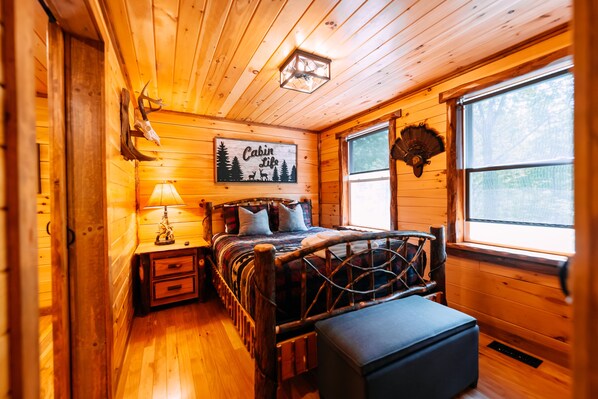 Un dormitorio de estilo cabaña con cama, lámpara de noche y un letrero que dice 'Cabin Life'.