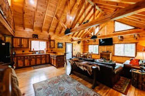 L’intérieur d’une cabane en rondins comprend une cuisine, un coin repas et un salon.