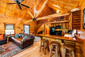 L’intérieur d’une cabane en rondins comprend un salon, une cuisine et un escalier.