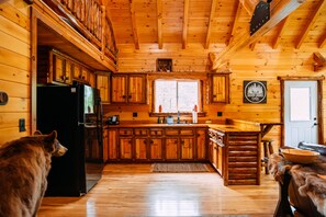Een houten cabin met keuken, eethoek en een groot raam.