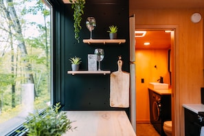 Une cuisine moderne avec des étagères en bois, une plante suspendue et une planche à découper en bois.