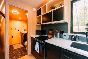Une cuisine moderne équipée d’une cuisinière, d’un évier et de meubles de rangement en bois.