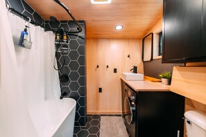 Une cuisine compacte comprenant un évier, un lave-linge et un petit plan de travail.