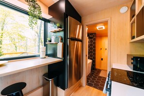 Une cuisine moderne dotée d’un réfrigérateur en acier inoxydable, d’un plan de travail en bois et offrant une vue sur l’extérieur.